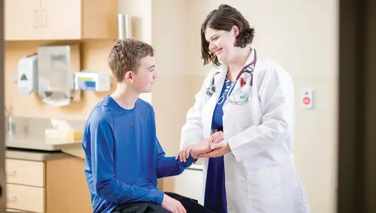 Gundersen doctor helping teenage boy with wrist injury.