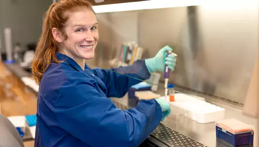 Female Lyme disease researcher smiling at camera while working.