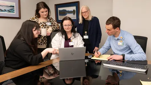 Five research navigation professionals collaborating in conference room.