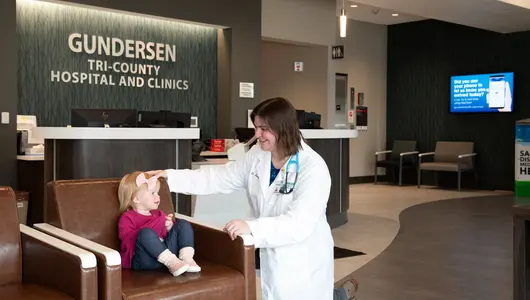 Gundersen Tri-County physician with toddler in hospital lobby.