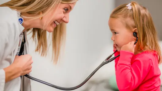 Young girl patient listening to the heart of a provider with a stethoscope