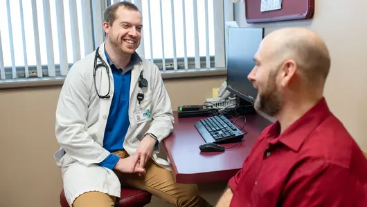 Gundersen physician assistant smiling and seated across from patient in exam room.