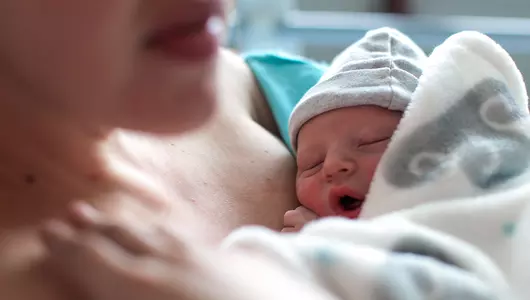A newborn baby boy breastfeeding for the first time in hospital, directly after a caesarean section