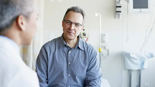 Doctor talking to mature male patient in hospital room