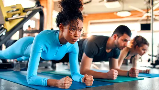 Slim women african american and caucasian ethnicity and muscular man in sportswear doing plank exercise on rubber mat in gym club.