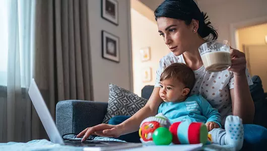 mother with baby on lap looking at laptop