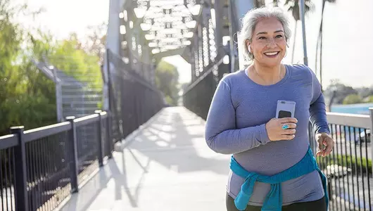 older woman smiling while jogging outside