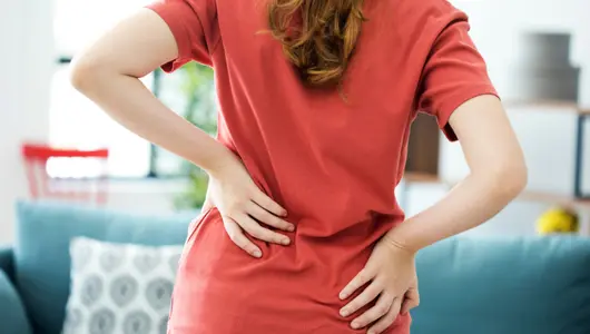 Woman in pain holding her side and back