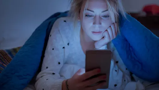 woman scrolling on smart phone at night in the dark