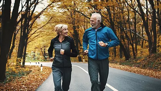 a couple jogging on a road in the fall
