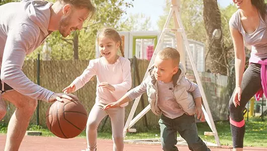 two parents playing basketball with children