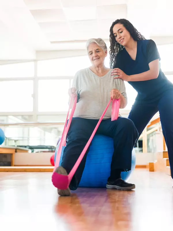 Senior woman stretching leg with exercise band
