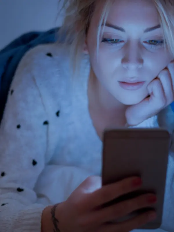 woman scrolling on smart phone at night in the dark
