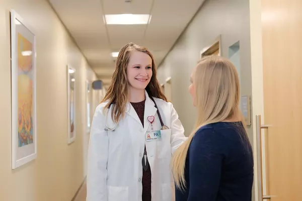 physician-assistant-looking-and-smiling-at-patient