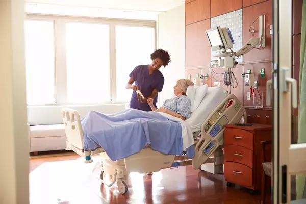Nurse caring for older patient in hospital bed.