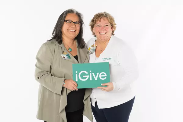 Two coworkers holding an iGive sign.
