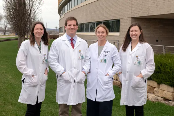 Four Gundersen general surgery residents standing in white lab coats outside hospital.