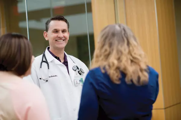 Male doctor talking and smiling with two adult female patients.