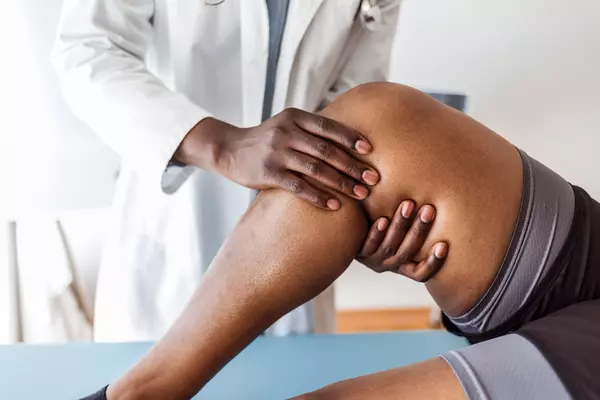Doctor checking knee of young man in doctor's office.