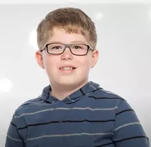Boy smiling wearing glasses and braces.