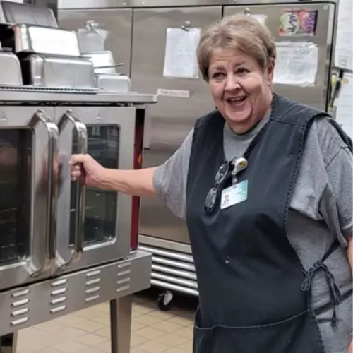 Dietary worker smiling in hospital kitchen.