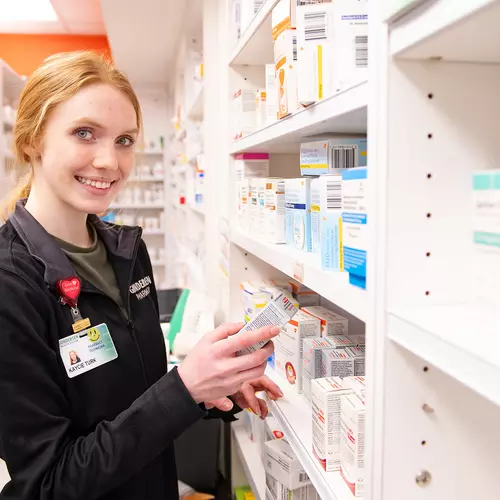 pharmacy-technician-holding-box-of-medication-in-supply-room
